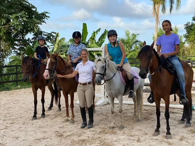 Equestrian trainer posing with family on horseback at Rainforest River Ride Adventure in El Yunque National Rainforest, Rio Grande, Puerto Rico