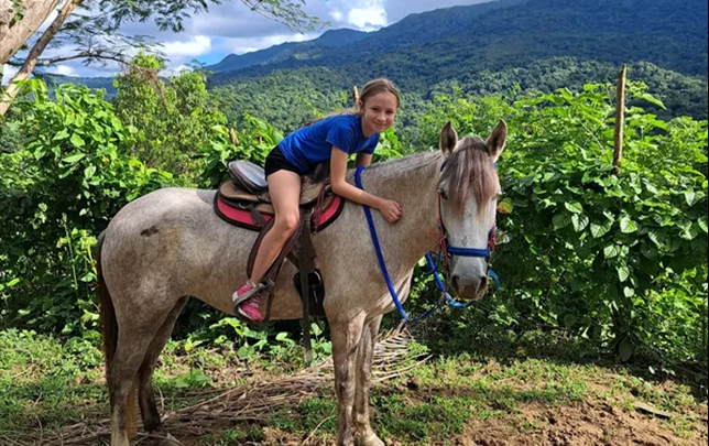 Young rider on horseback at Rainforest River Ride Adventure in El Yunque National Rainforest, Rio Grande, Puerto Rico